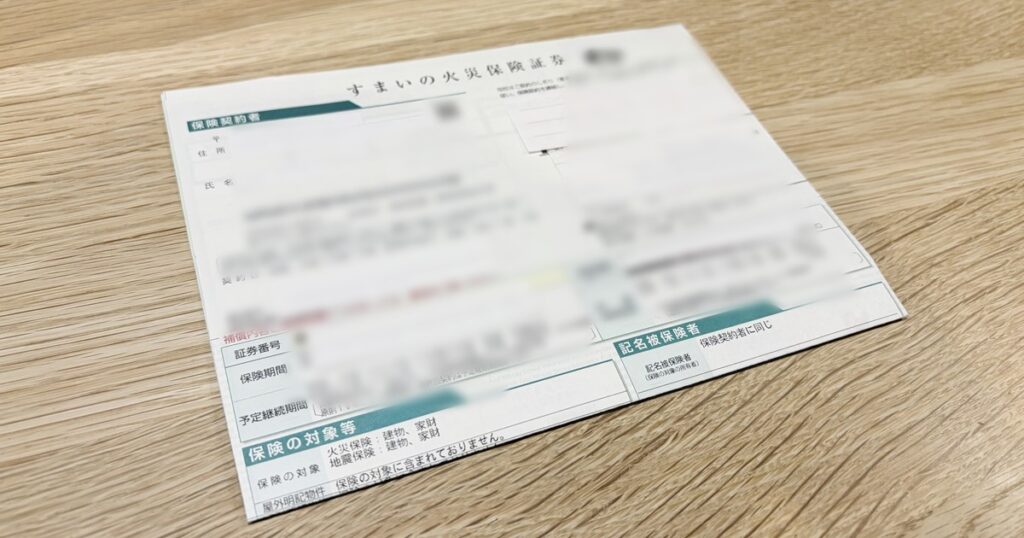 木のテーブルに置いた火災保険の保険証券