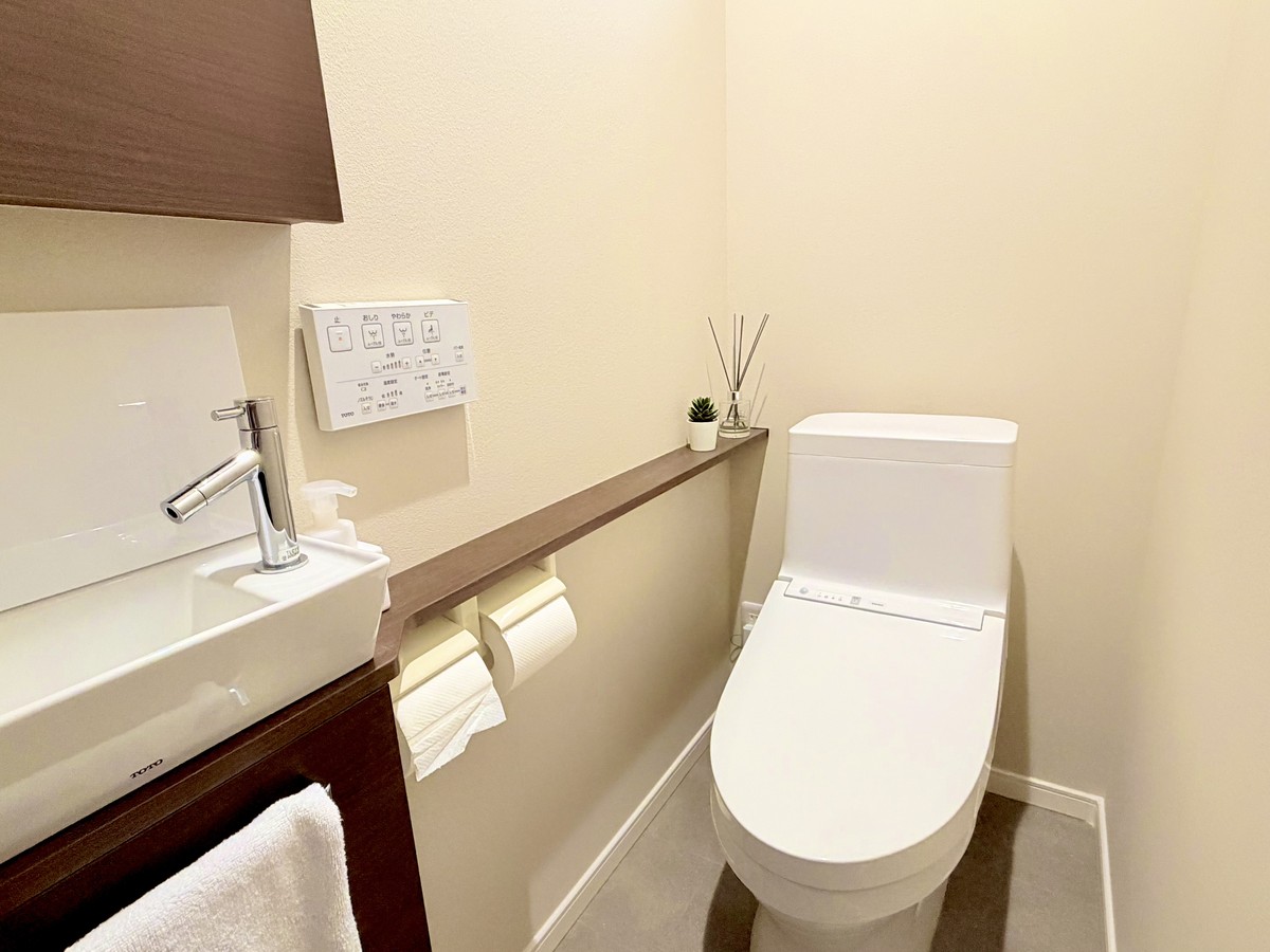 2階トイレの4面ベージュのクロス（リリカラXB-749）と濃い茶色の収納棚